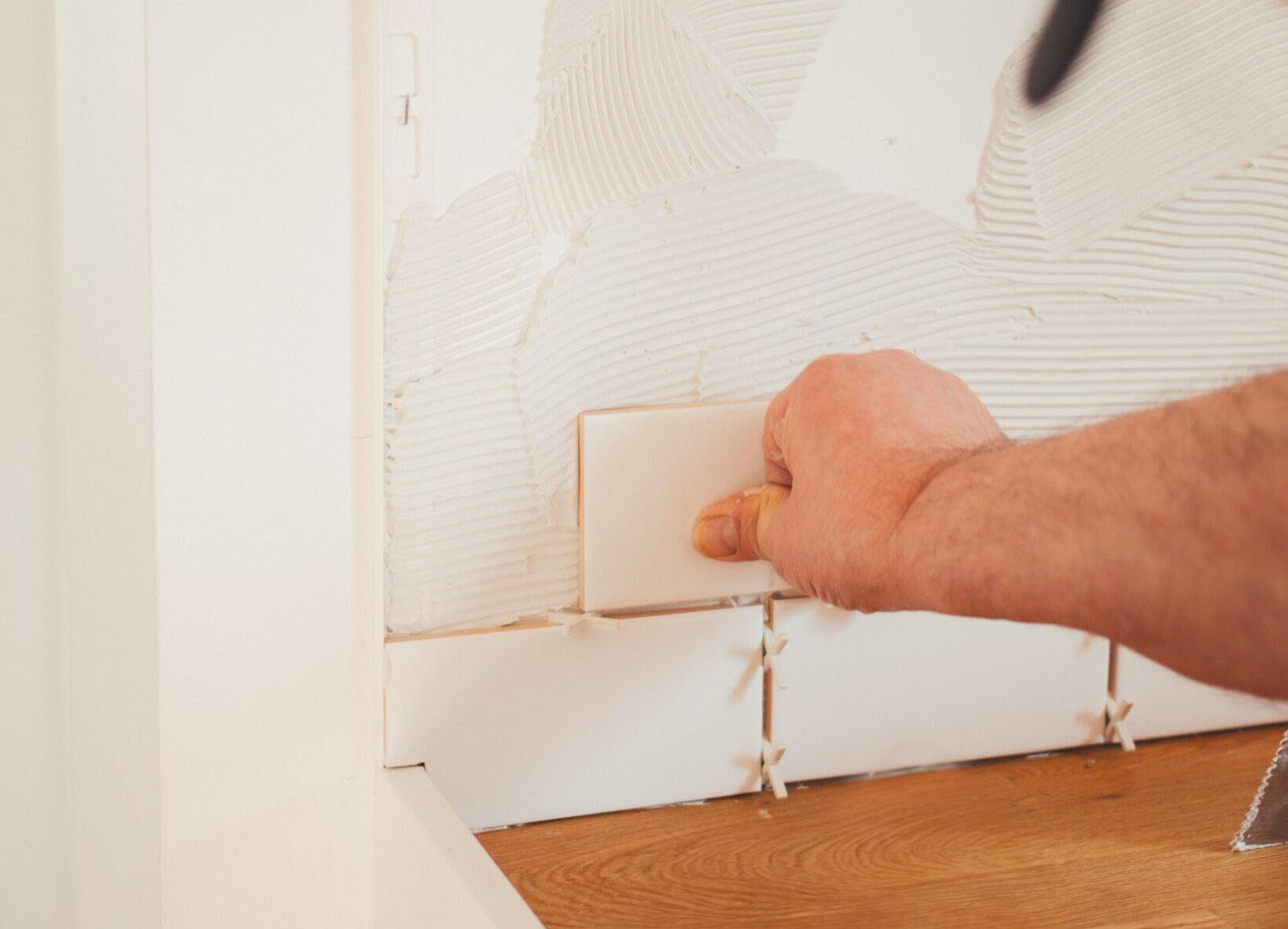 A person installing tiles to a wall