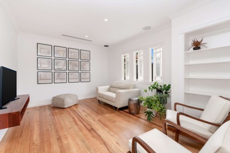 A living room with solid wood flooring, filled with furniture and flat screen tv