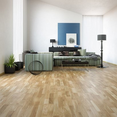 A living room with a sofa, table, standing lamp and wooden flooring.