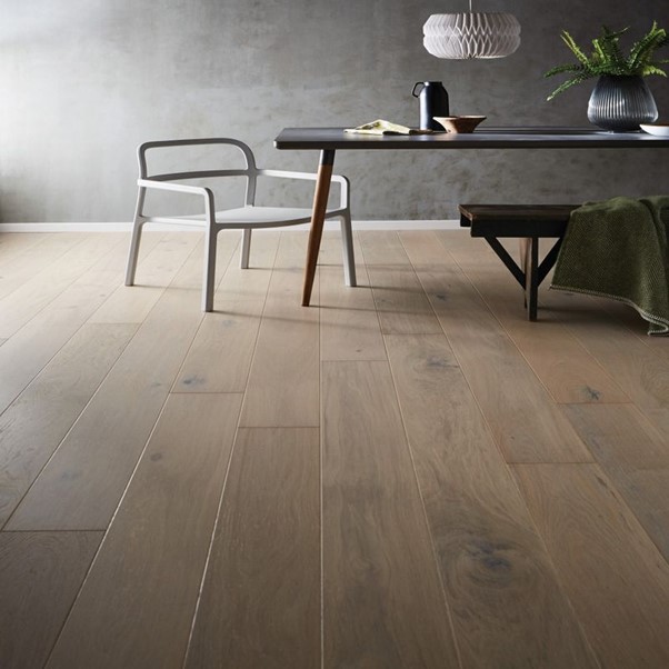 A table and chair in a room with oak wood flooring.