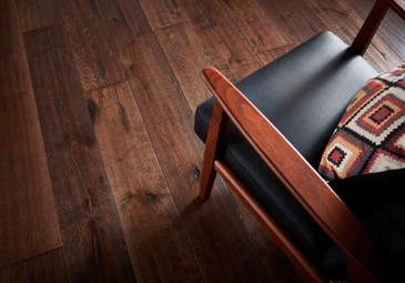 A chair with a cushion on it and walnut flooring.