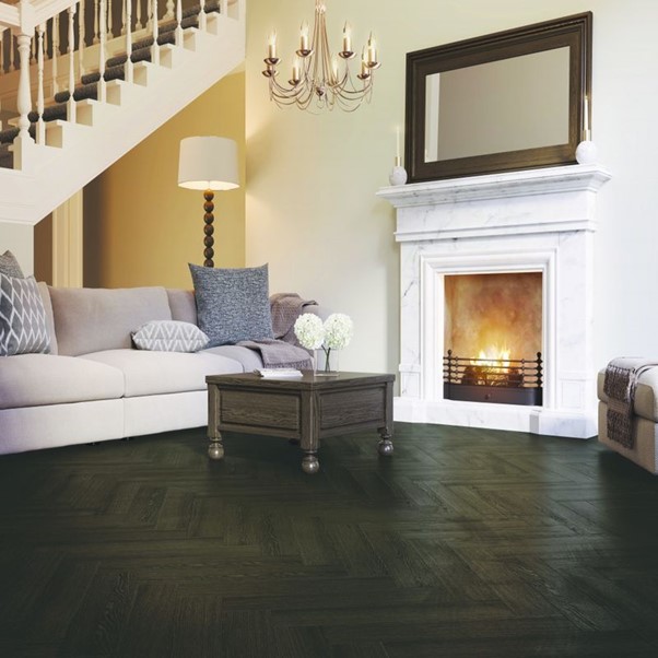 A living room with a fireplace, sofa, chandelier and wood flooring.