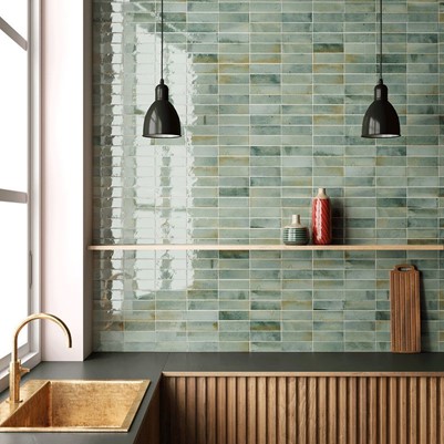 A kitchen with a sink, shelves and rectangular green tiles on the wall.