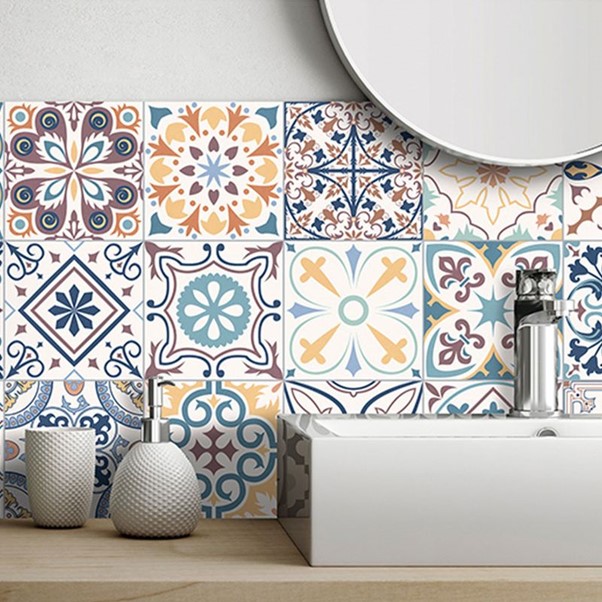 A bathroom sink with a mirror and colourful, patterned tile wall.
