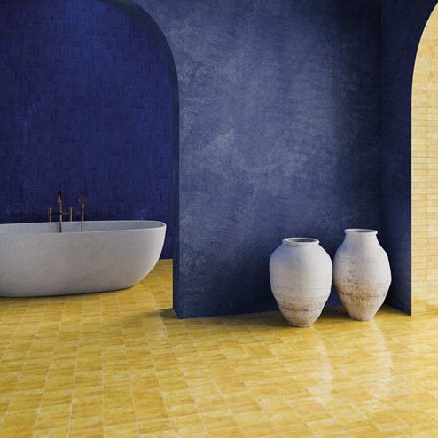 A bathroom with a tub, two vases, blue walls and yellow floor.