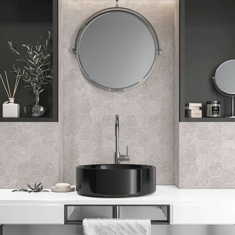 A bathroom with a round mirror, a sink and hexagonal tiles on the wall.