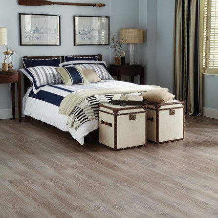 A bedroom with wood flooring, a bed and two boxes.