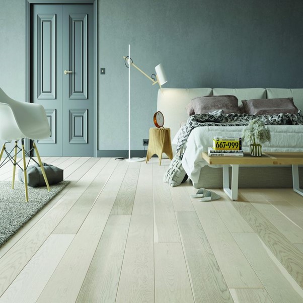A bedroom with a bed, table and vertical wood effect flooring.