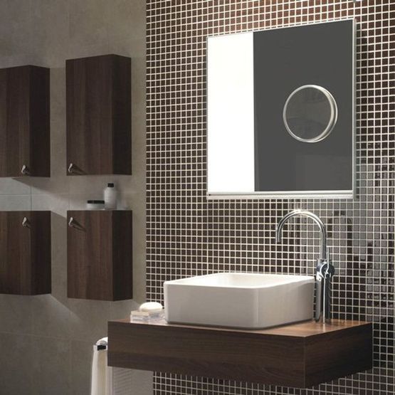 A modern bathroom with a floating basin, low lighting and small tiles on the wall