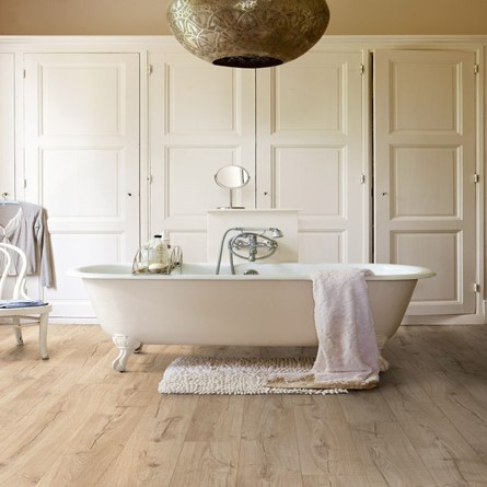 A bathroom with laminate flooring and a freestanding bath.