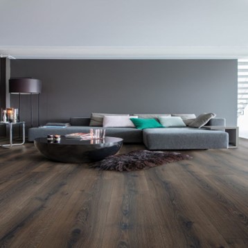 A modern lounge with wide plank laminate flooring.