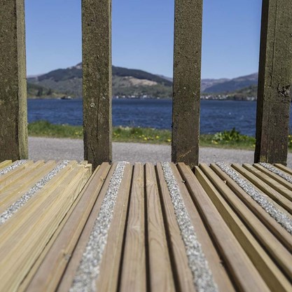 A wooden deck with slip resistant tape and a lake and mountains in the background.