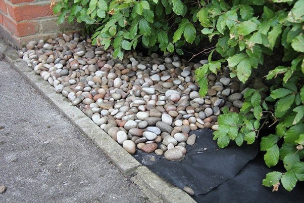 A rock garden with black weed control fabric membrane.