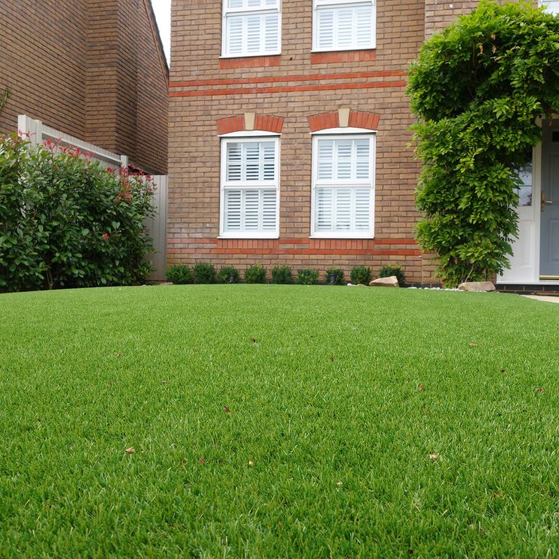 An artificial grass lawn in front of a brick building.