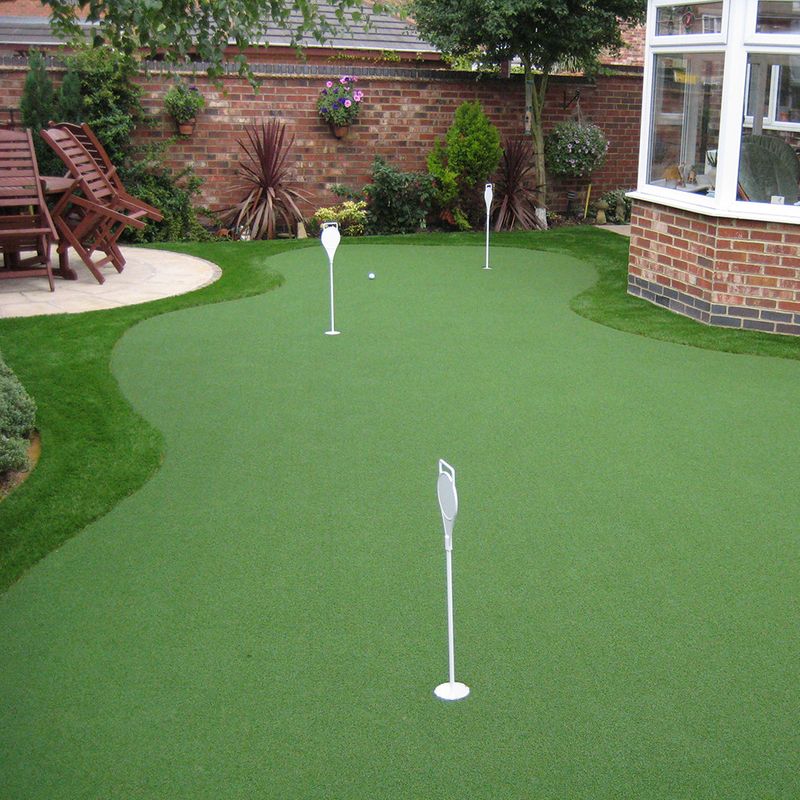 A golf course with artificial grass and a brick wall. 