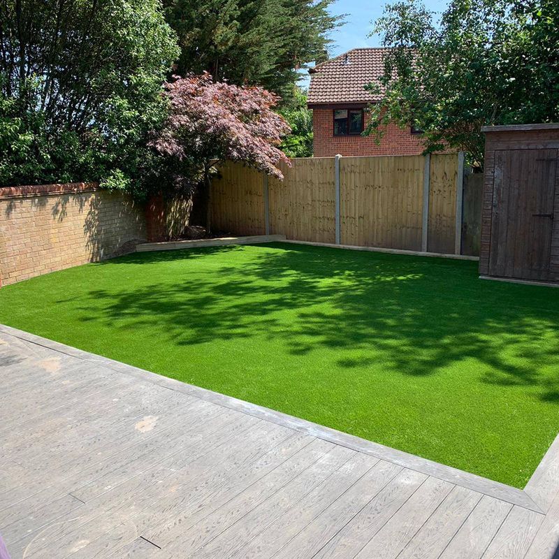 A rectangular lawn with artificial grass and wooden deck. 