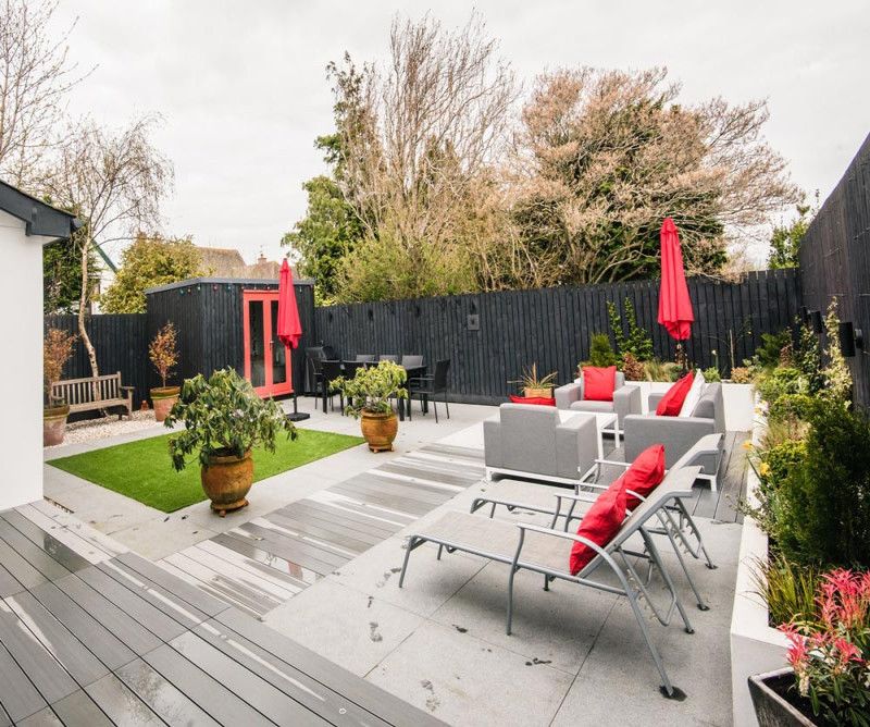 A patio area with decking, chairs and a lawn.
