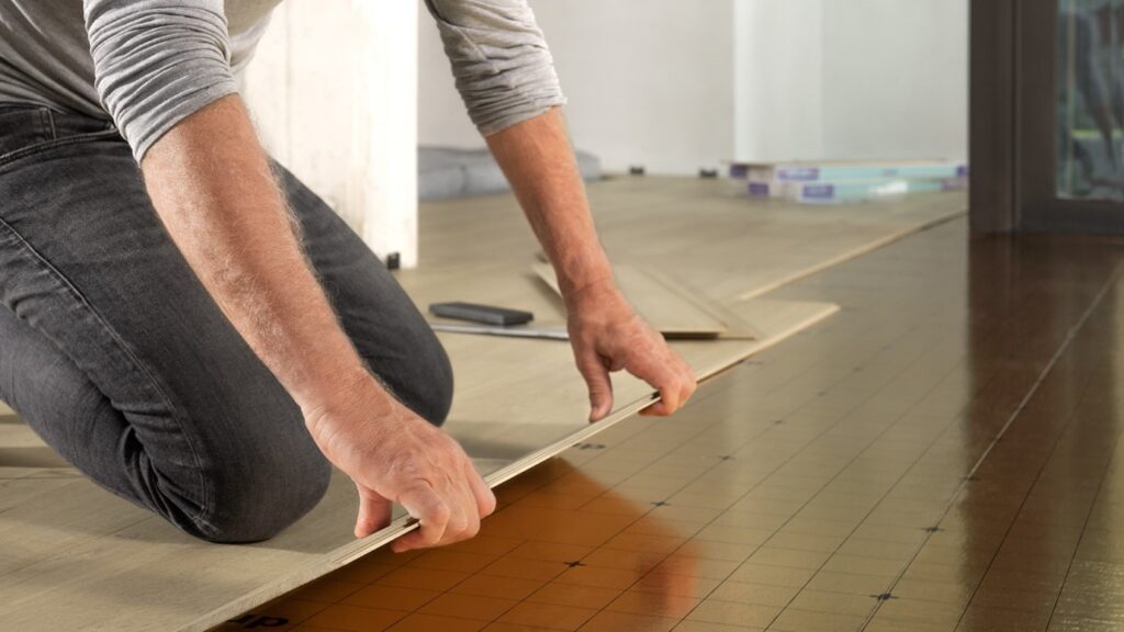 A person laying laminate flooring. 