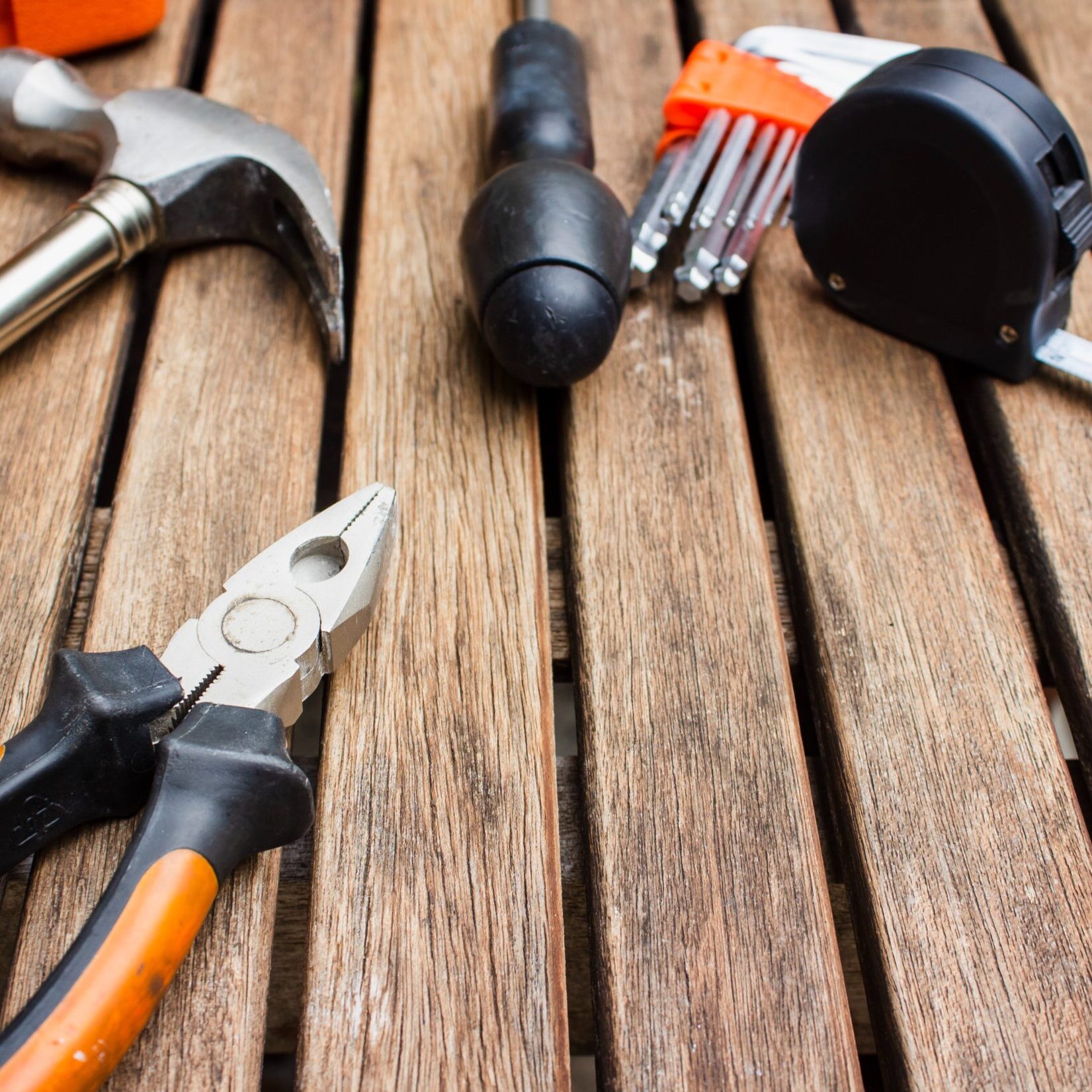 An array of tools on a wooden structure, including a hammer, pliers, a tape measure and more