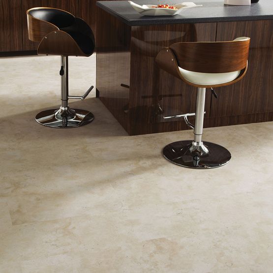 A kitchen with deep wooden cabinets, dark brown stools and LVT flooring in a neutral tone