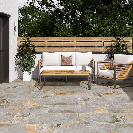 A garden patio with a white sofa, a wooden table and porcelain outdoor tiles
