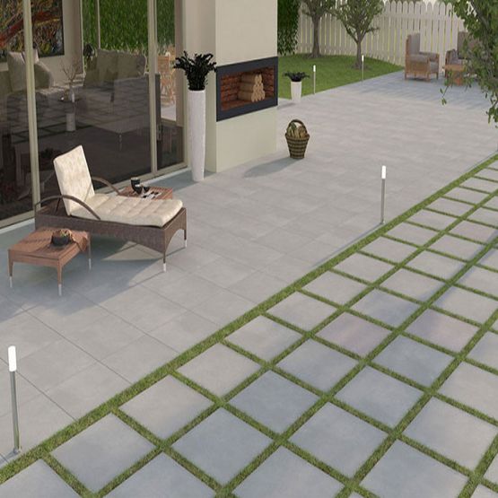 A patio and garden area with grey porcelain paving slabs and a deck chair