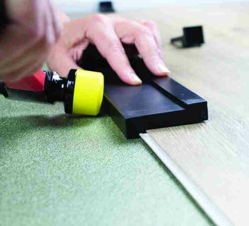 A mallet next to a tapping block installing laminate flooring.