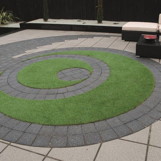 Concrete paving slabs around a patch of circular lawn