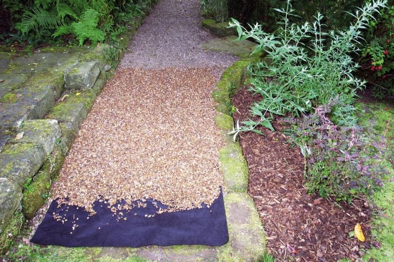 A path with gravel and a black weed control membrane. 