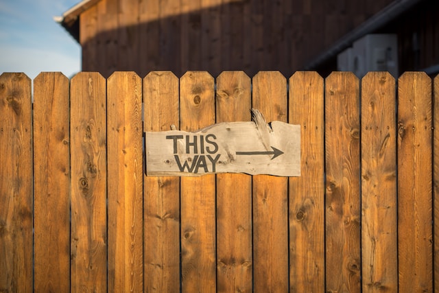 Wooden fence with a 'This Way' sign