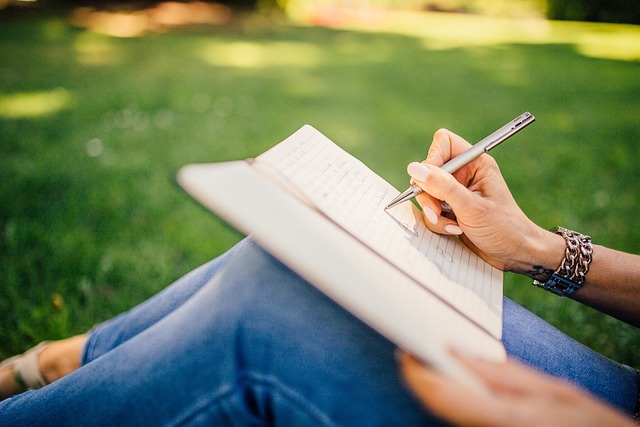 Woman writing in a notebook while sitting on the grass