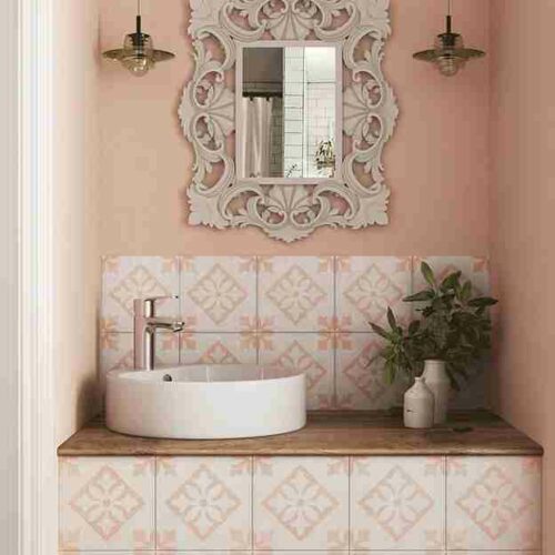 A sink and mirror above a counter with pink, patterned tiles with pressed edges.