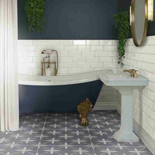 A bathroom with a sink, bathtub and blue, patterned floor tiles with pressed edges and white wall tiles.