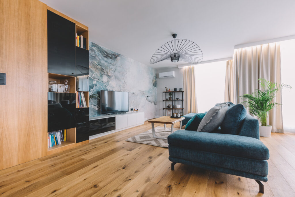 An open lounge with dark cabinets and sofa, with a blue mottled marble effect feature wall. The wood flooring is rustic with natural wood knotting, laid in a brick bond parquet pattern